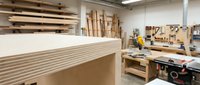 Professional woodworking workshop interior with stacked lumber planks and carpentry tools for furniture making and construction projects.