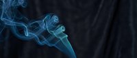 Delicate blue smoke swirling gracefully against a dark background, creating an ethereal, mysterious atmosphere with flowing abstract shapes.