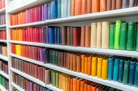 Colorful rows of books arranged by spectrum colors on white library shelves create vibrant rainbow pattern, showcasing organized collection for education and reading.