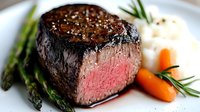 Juicy grilled beef tenderloin steak cooked medium rare, served with fresh asparagus spears, baby carrots and herbs on white plate, close up view of meat texture.