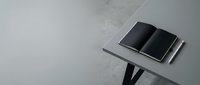 Two black smartphones with blank screens displayed on a modern metal stand against a minimalist gray concrete background for tech product showcase and digital device marketing.