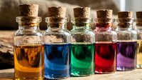 Colorful essential oils and liquid extracts in glass bottles with cork stoppers, arranged in a row outdoors for aromatherapy, perfumery, and cosmetic product design.
