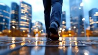 Professional businessman walking on wet city street at dusk with illuminated skyscrapers and bokeh lights reflecting on pavement creating urban corporate atmosphere.