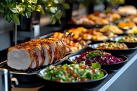 Sliced roasted pork tenderloin with crispy crust served on black plates alongside fresh colorful salads and appetizers at catering buffet table. Perfect for menu design.