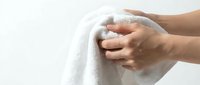 Hands gently holding soft white towel against clean background for spa wellness hygiene and bathroom concepts.