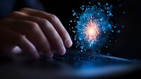 Glowing digital particle explosion with blue light emerging from touchscreen device, hand interacting with futuristic holographic display in dark environment.