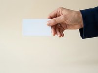Male hand holding blank white card against neutral background, suitable for business presentations, marketing materials, and corporate communications.