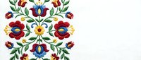 Traditional folk art floral embroidery pattern with colorful flowers and leaves on white fabric background for textile and craft projects.