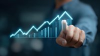 Businessman pointing at glowing blue financial chart showing upward trend with house symbol, representing growth in real estate market and investments.