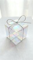 Holographic iridescent gift box with silver ribbon bow on white background for holiday celebrations and special occasions packaging design.