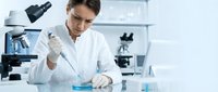 Female scientist in white lab coat conducting research experiment with pipette in modern laboratory setting for medical and scientific studies.