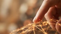 Hand touching glowing golden network lines with sparkling light particles, representing digital connection, technology innovation, and data communication in business environment.