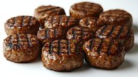Juicy grilled beef patties with classic grill marks on white background, close-up view showing meat texture and caramelized surface for restaurant menu or cooking.