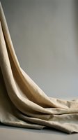 Soft beige linen fabric draped elegantly with natural folds and wrinkles creating organic texture and shadow play against neutral background for interior design.
