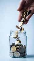 Hand dropping coins into glass jar for savings and financial planning concept with motion blur effect on falling money.