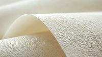 Soft wave of natural cotton fabric with delicate texture and gentle folds in cream color creates minimalist organic background for design projects.