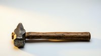 Vintage rusty hammer with wooden handle isolated on white background for construction and repair projects.