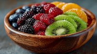 Fresh mixed berries and kiwi slices in wooden bowl with blackberries, raspberries, strawberries and orange segments for healthy breakfast or snack.