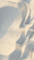 Soft sand texture with natural wind patterns and gentle shadows creating organic waves and ripples for beach vacation and summer travel backgrounds.