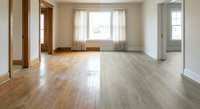 Empty modern apartment interior with hardwood floors and large windows for real estate listings and home staging concepts.