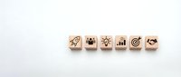 Wooden cubes with business icons including rocket, teamwork, innovation, growth chart, target and handshake representing startup strategy concepts.