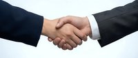 Business handshake between two professionals in dark suits on white background symbolizing partnership, agreement, deal, cooperation and success.