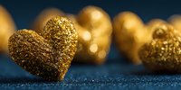 Golden glitter hearts on dark blue background with soft bokeh effect. Romantic festive decoration for Valentine's Day, wedding, or anniversary celebration.