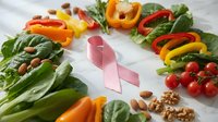 Fresh organic vegetables and pink ribbon symbolizing breast cancer awareness and healthy nutrition for disease prevention.