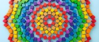 Colorful rainbow mosaic pattern with vibrant geometric squares arranged in concentric circles creating radial symmetry on white background for creative design.