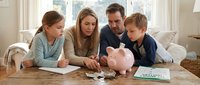 Caucasian family with two children learning about money management and savings with piggy bank at home table during financial education session.