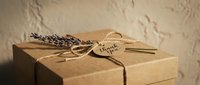 Kraft paper gift box tied with twine, dried lavender sprig, and a thank you tag, rustic handmade style on a textured background.