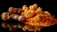 Fresh turmeric root and dried powder with crystallized ginger on black reflective surface, dramatic lighting highlights golden orange spice ingredients for cooking.