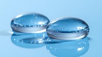 Transparent water drops on blue surface with reflection. Macro photography showing surface tension and optical distortion creates abstract natural pattern.