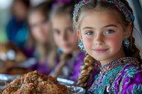 Young Caucasian girl in traditional colorful folk costume with braided hair and floral headband smiles warmly during festive celebration with traditional food on table.