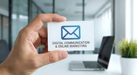 Professional hand holding white business card with email icon and digital communication online marketing text in modern office environment.