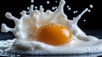 Raw egg yolk creating dramatic splash in white liquid against dark background, high-speed macro photography capturing food motion and texture detail.