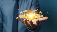 Businessman holding glowing team icons in cupped hands representing human resources management and leadership development concepts.