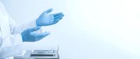 Healthcare professional wearing blue latex gloves presenting or explaining medical information in clinical laboratory setting with equipment.