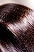Close-up macro shot of glossy brown hair strands showing smooth texture and shine, highlighting natural movement and healthy appearance for beauty and haircare concepts.