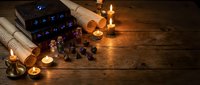 Mystical fortune telling setup with tarot cards, crystal ball, candles and scrolls on wooden table creating atmospheric divination scene for spiritual practices.