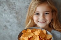 Happy blonde girl holding bowl of heart-shaped cookies, smiling at camera. Childhood joy, baking, homemade treats for family bonding and kitchen activities.