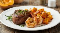 Grilled beef steak with roasted potatoes and shrimp served on white plate for fine dining, restaurant menu, food photography, culinary presentation.