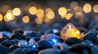 Glowing amber stone among dark pebbles with warm bokeh lights creating magical evening atmosphere for meditation and wellness concepts.