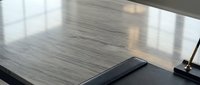 Modern office desk with sleek wood grain surface and black laptop in minimalist workspace setting for business and productivity applications.