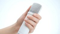 Hand holding white wireless microphone with silver mesh grille against clean background for broadcasting and recording applications.