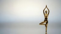 Golden metallic female figure in tree yoga pose on neutral gradient background for wellness and meditation designs.
