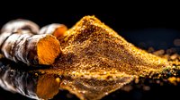 Fresh turmeric root and ground powder spice on dark background with reflection, aromatic Indian seasoning macro photography in golden colors.