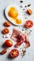 Sunny side up eggs with prosciutto ham, fresh cherry tomatoes, capers and spices on light background. Food composition for breakfast or brunch menu.
