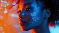 Young African American woman with glowing blue digital pattern projected on face against orange background, representing artificial intelligence and future technology.