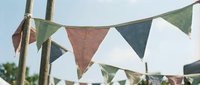 Colorful triangular bunting flags hanging on rope against sky creating festive outdoor party decoration for celebrations and events.